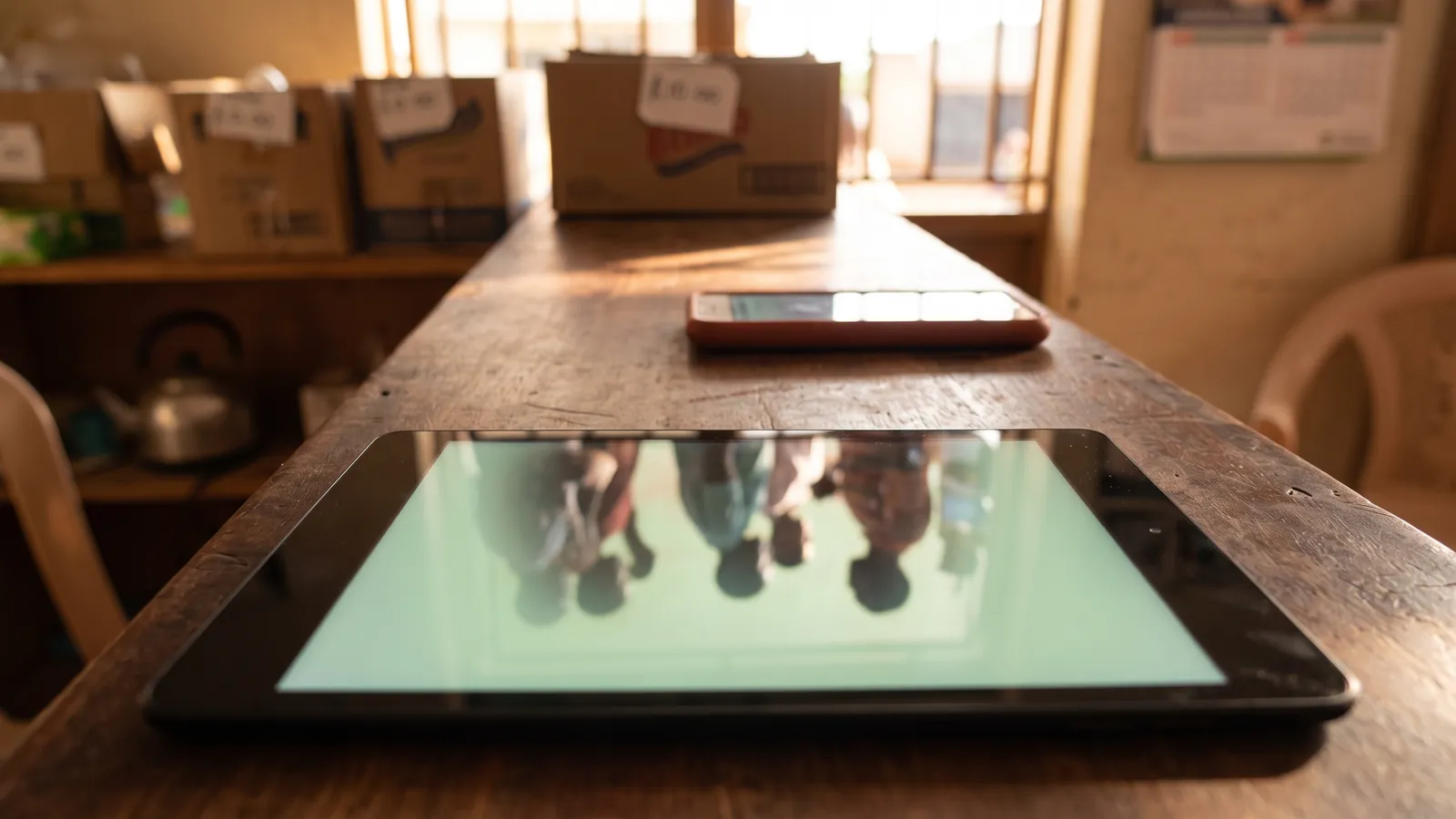 A tablet on a shop counter with the mobile data switched off, a queue of customers reflected in the screen
